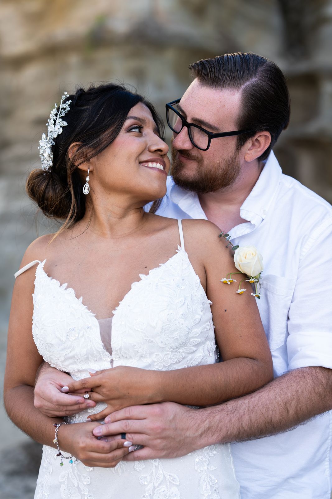 Groom embracing the bride from behind as they smile at each other