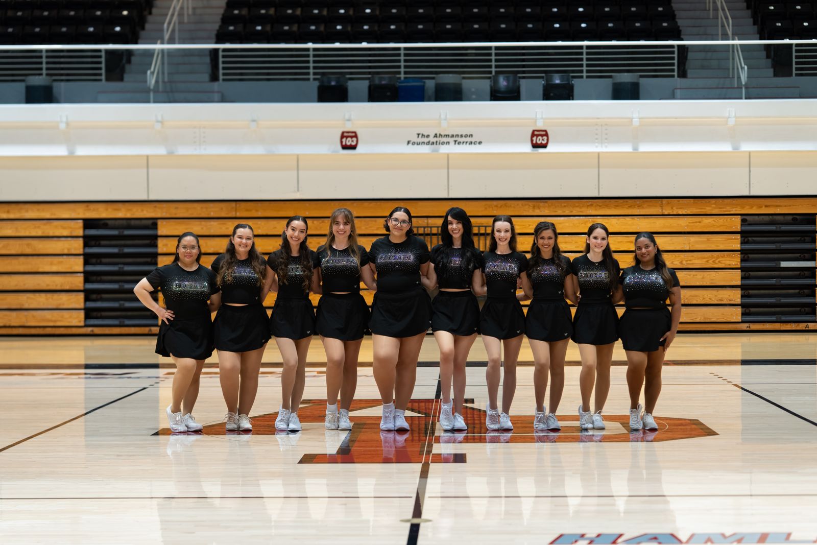 Dance team standing arm in arm at center court
