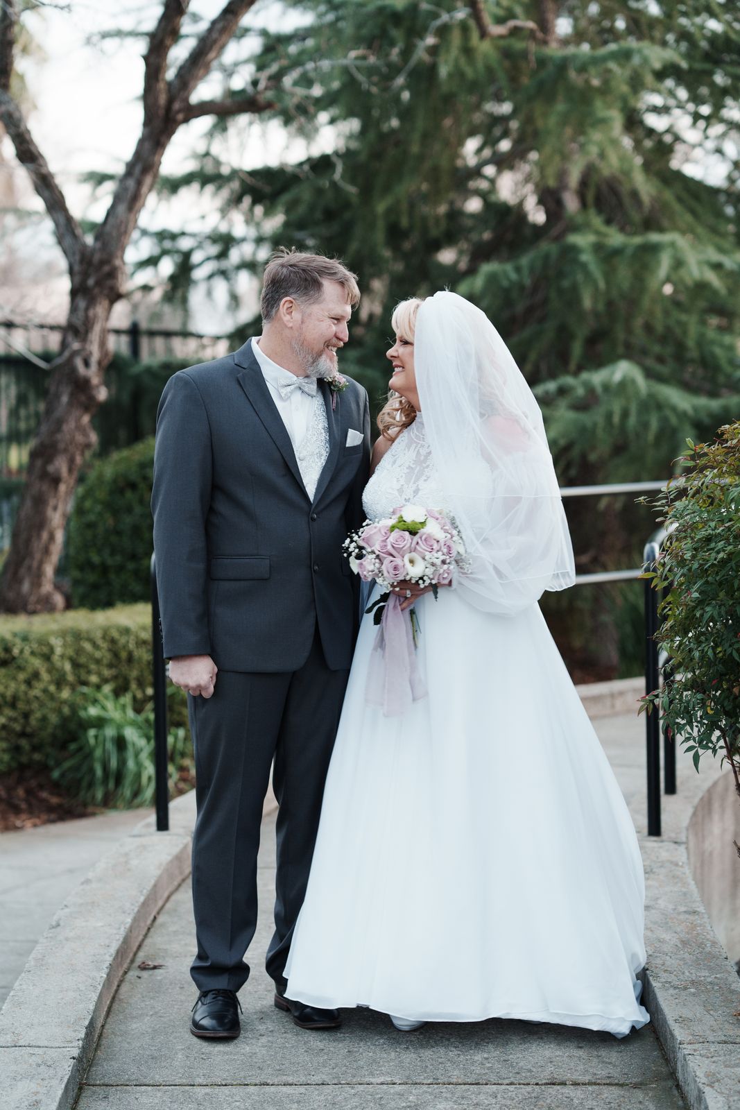 Bride and groom smiling at each other on a garden path