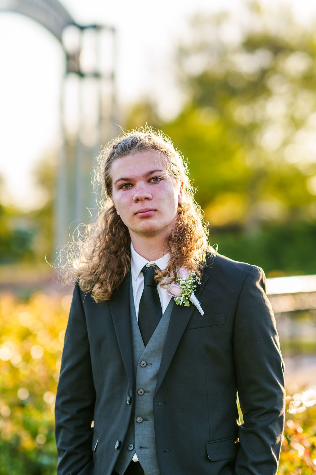 Young man in a suit and boutonniere in warm backlight