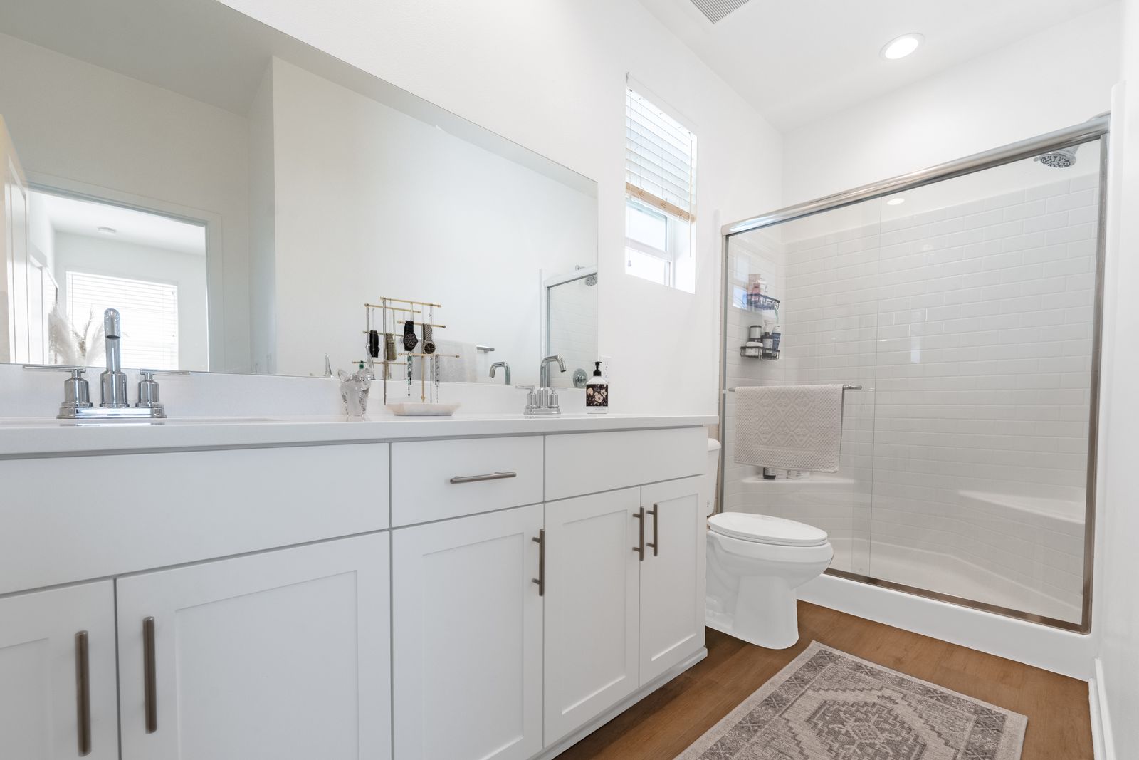 White bathroom with a glass shower and double vanity
